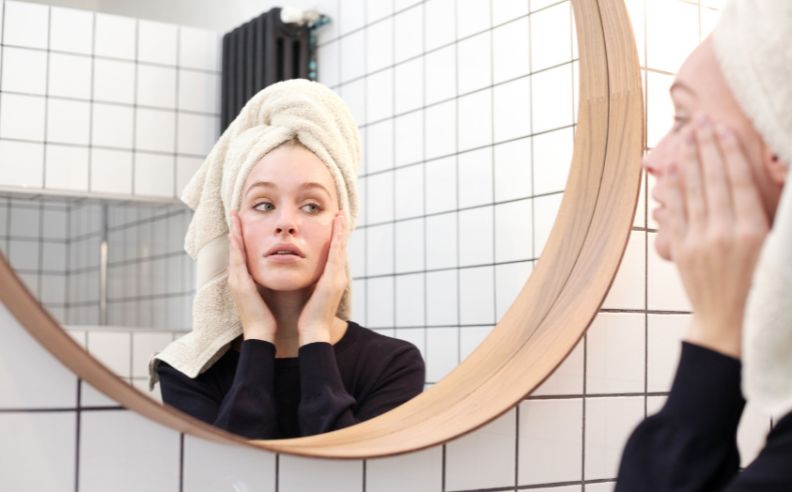 Femme inspectant sa peau grasse dans un mirroir rond