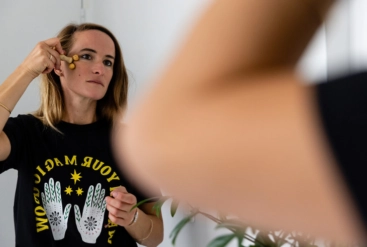 femme faisant un massage de son visage à l'aide d'un miroir pour avoir une belle peau