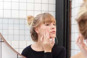 Femme examinant ses pores dilatés dans un miroir