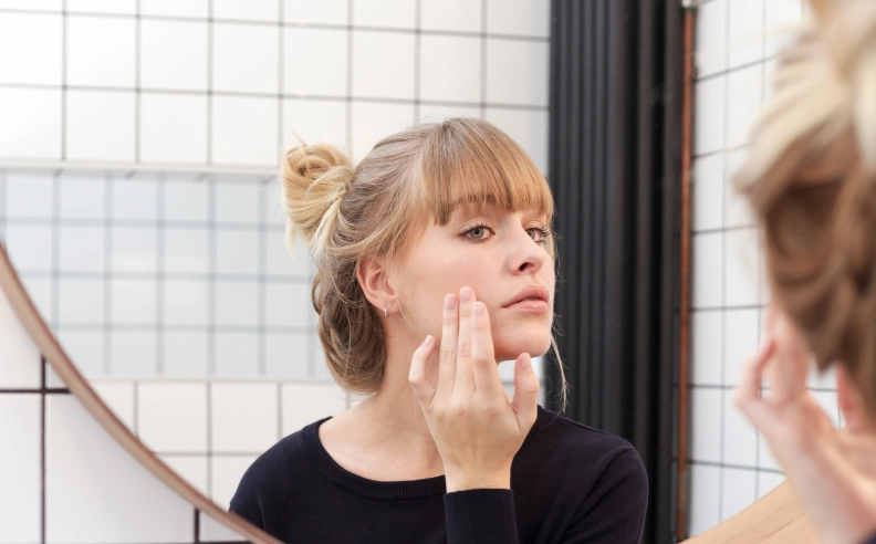 Femme examinant ses pores dilatés dans un miroir