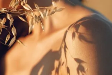 Zoom brut sur peau de jeune femme et ombre de végétaux