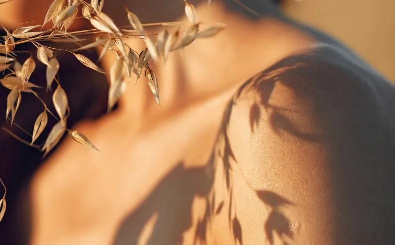 Zoom brut sur peau de jeune femme et ombre de végétaux