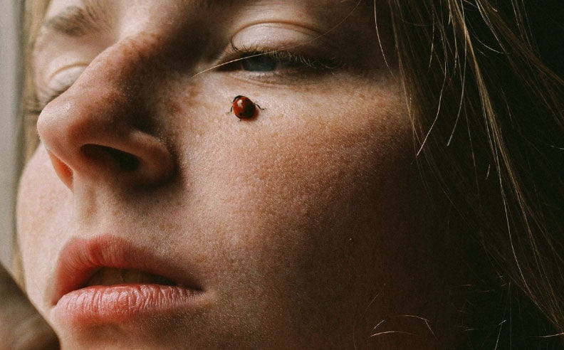Zoom sur la pommette d'une femme avec une coccinelle dessus